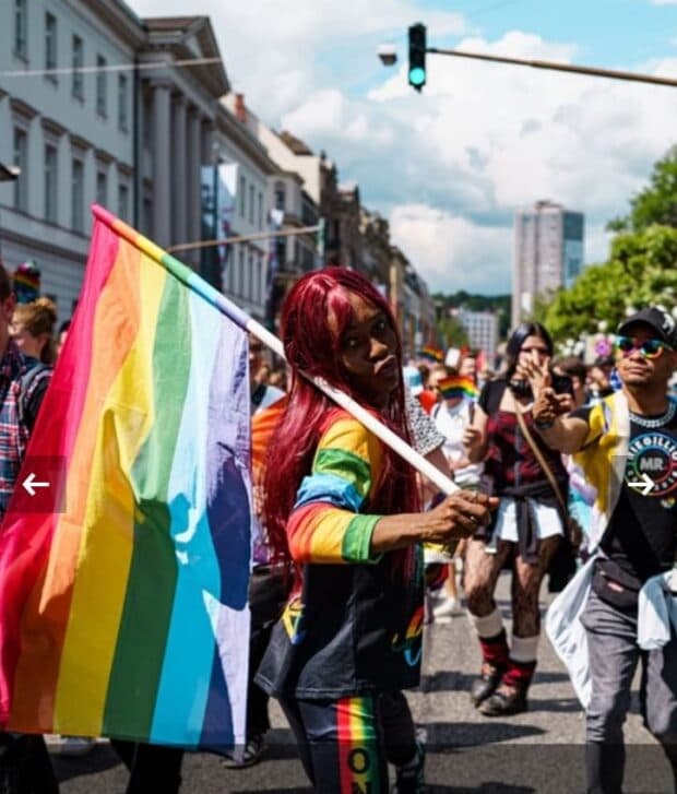 Person holding a rainbow flag while marching in a Pride parade.