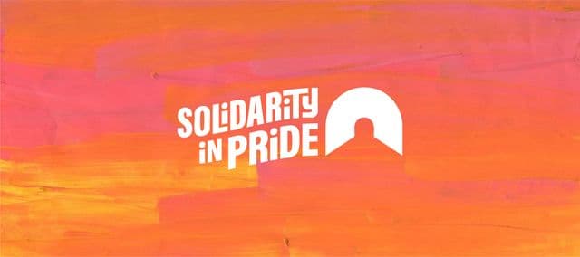 White “Solidarity in Pride” text on a pink-orange painted background.