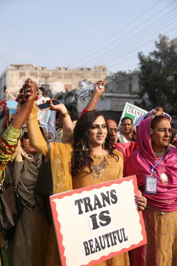 Person holding a “TRANS IS BEAUTIFUL” sign during a march.