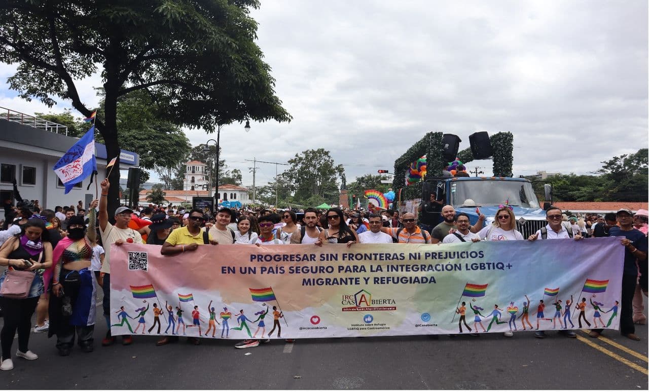 People marching with a large banner advocating for LGBTQI+ migrants and refugees.