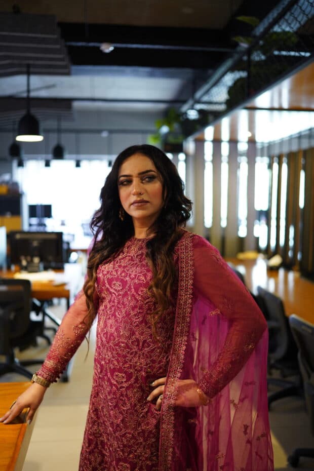 A person in a pink embroidered dress standing in an office space.