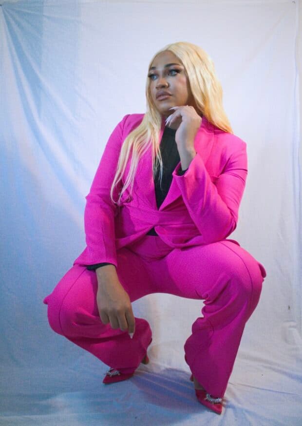 Person in a bright pink suit posing against a white backdrop.