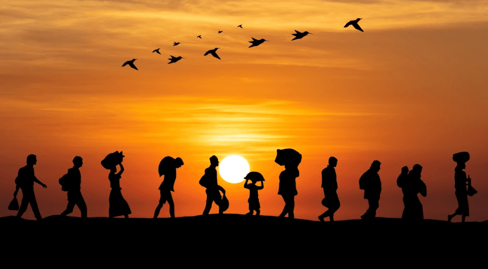 Silhouettes of people walking across a sunset