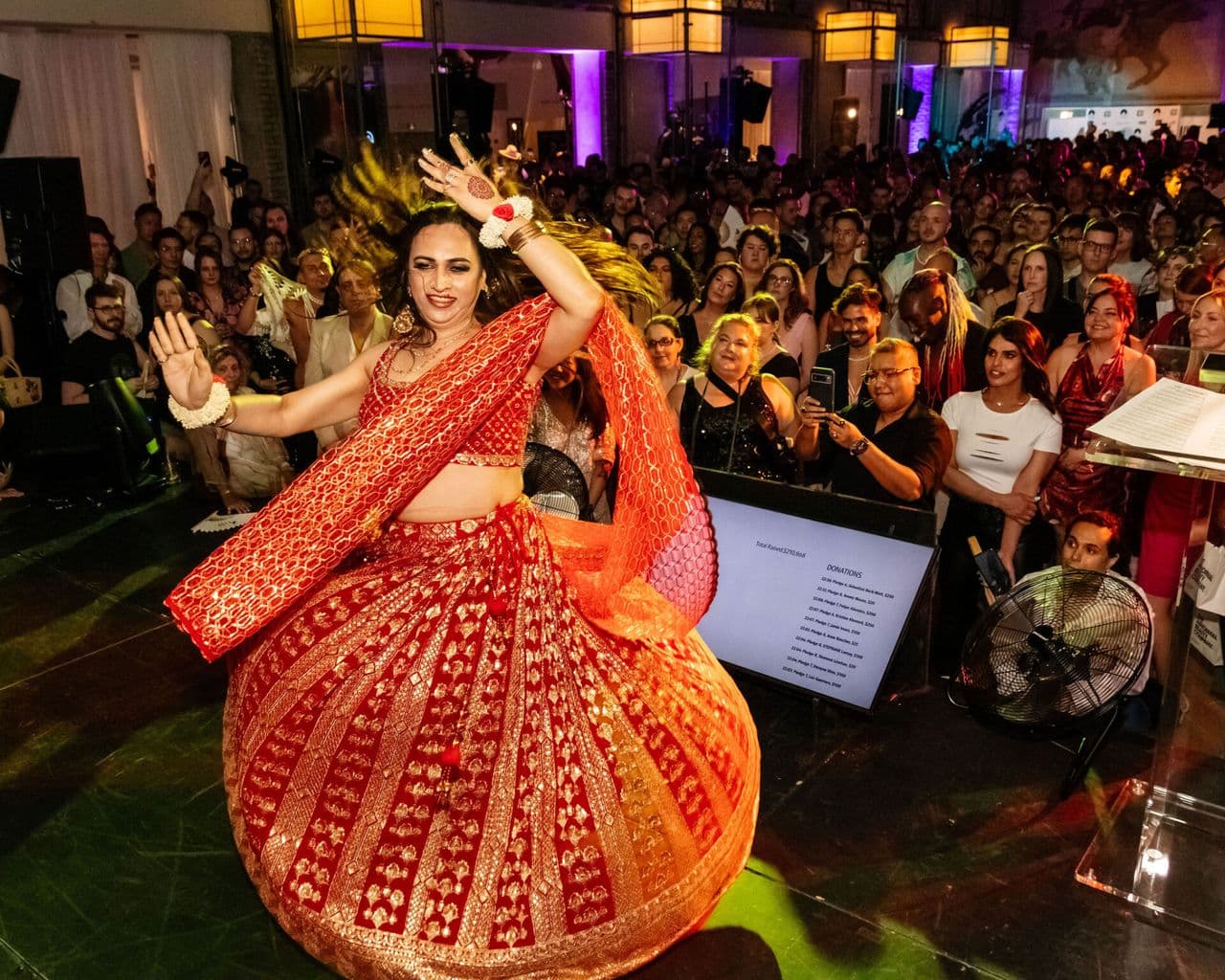 Person in a red and gold traditional dance outfit performing onstage.