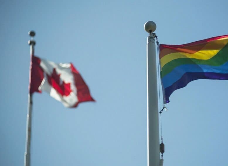 Canadian flag beside a pride flag.